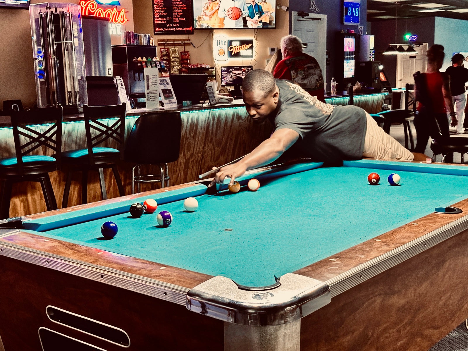 A NAPA of Pensacola player stretching across the table for a long shot at Nine Mile Billiards