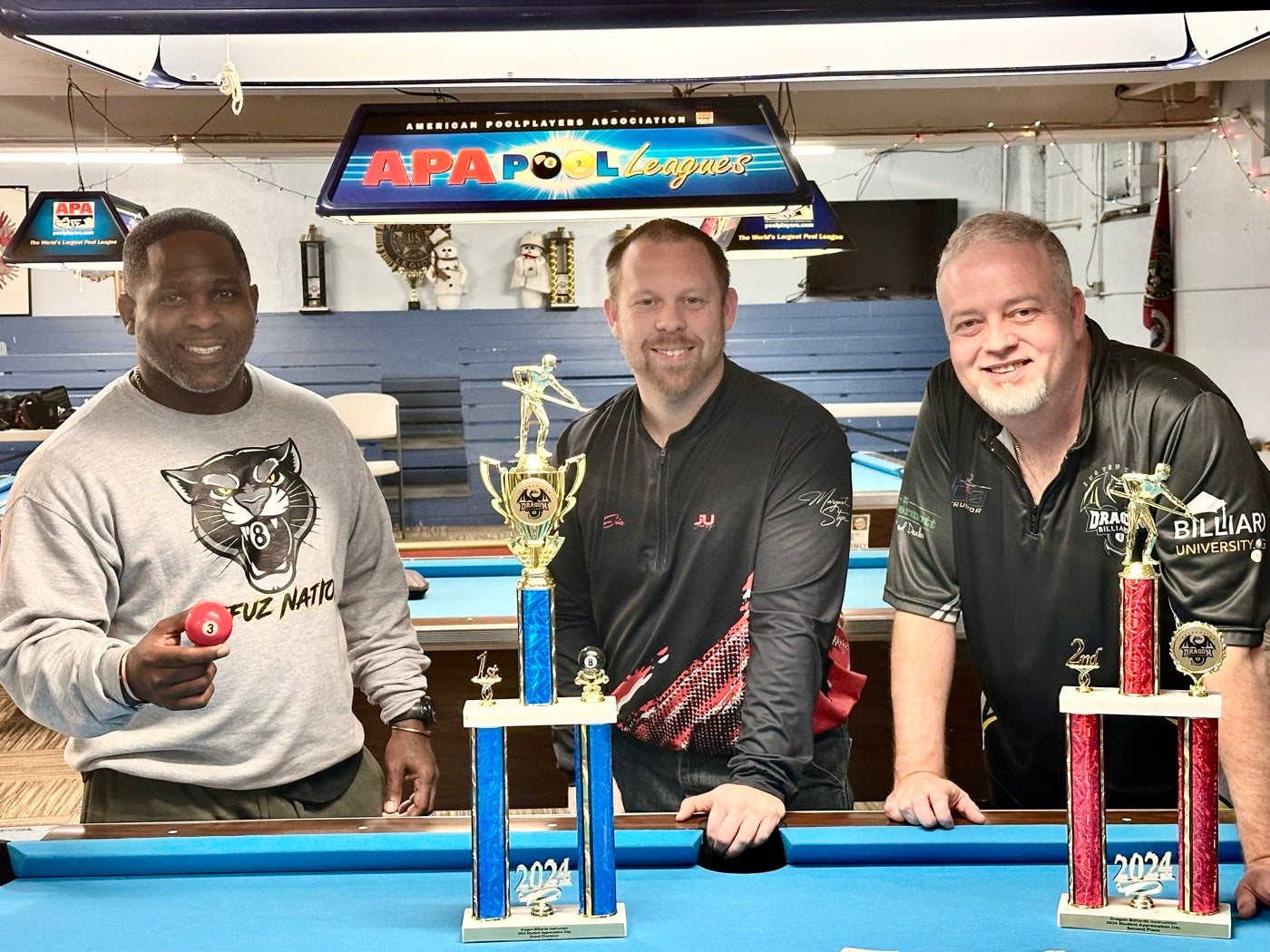 The instructor with two players holding APA league trophies