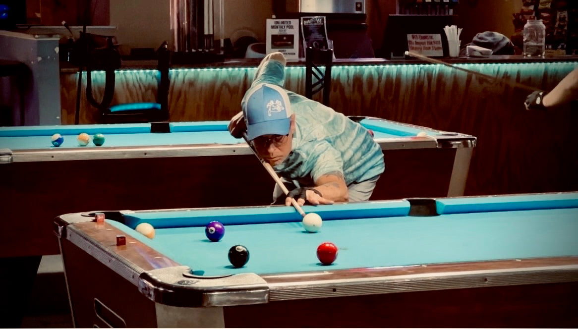 A NAPA of Pensacola player lining up a shot on the turquoise felt at Nine Mile Billiards