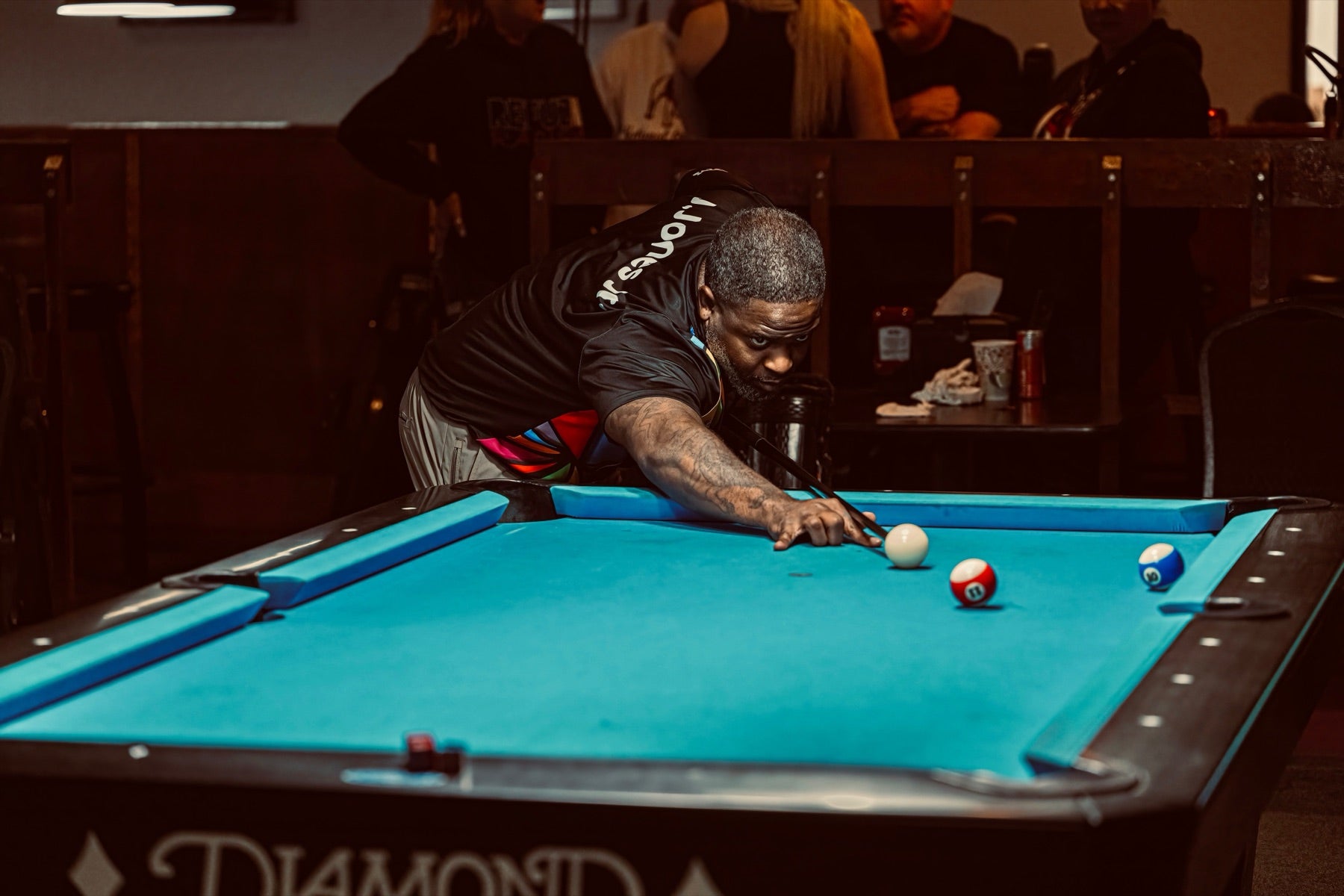 A NAPA of Pensacola player lining up a shot on the blue felt during a league night at Nine Mile Billiards