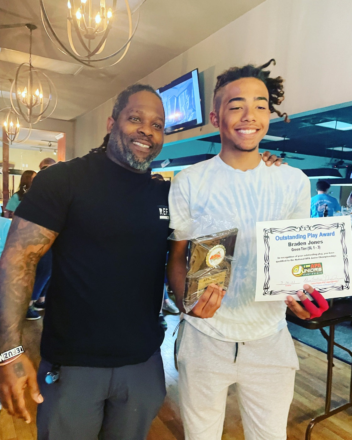 The NAPA of Pensacola instructor with a young student holding an APA Junior Championships Outstanding Play Award
